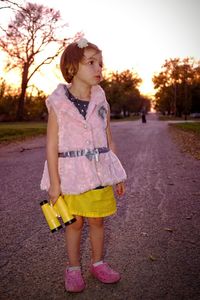 Girl looking away while standing on road against sky