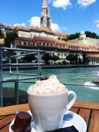 Close-up of coffee with whipped cream by buildings in background