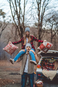 Man carrying girlfriend on shoulder in forest