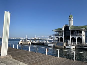 View of building by sea against clear blue sky