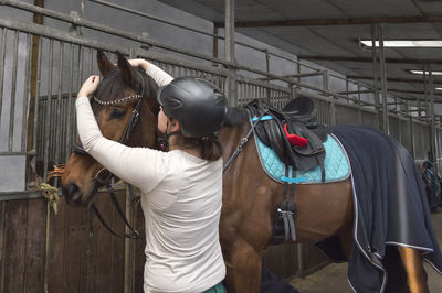 Rear view of woman with horse standing stable