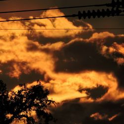 Low angle view of power lines against cloudy sky