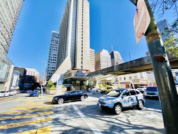 Vehicles on road amidst buildings in city against sky