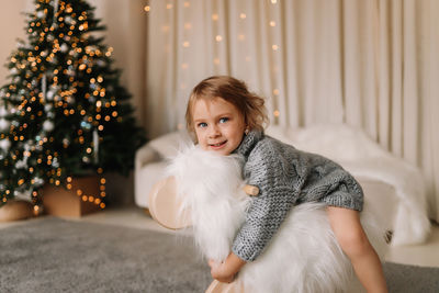 Little girl child in knitted sweater having fun playing christmas holiday in decorated house