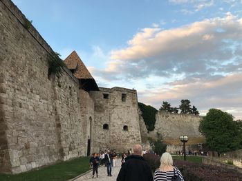 People at historical building against sky