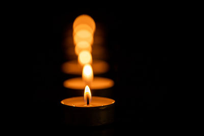 Close-up of lit candle against black background