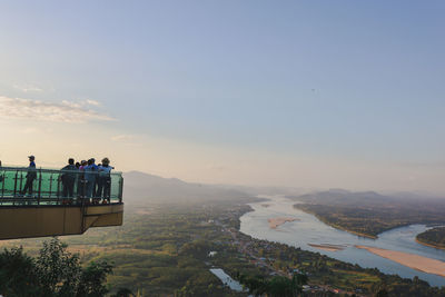 People looking at cityscape against sky during sunset