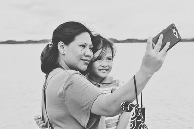 Portrait of mother and daughter standing against sea
