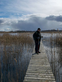 Man standing on pier over lake against sky