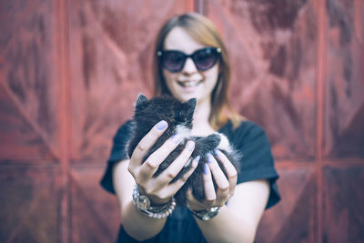 Portrait of smiling young woman holding kitten