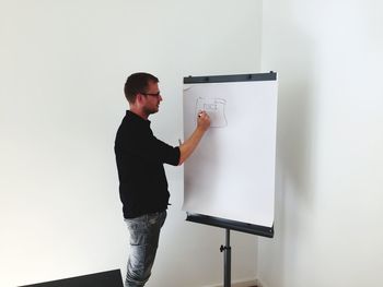 Man drawing in paper against wall