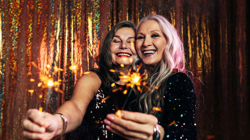 Portrait of smiling senior women holding sparkler