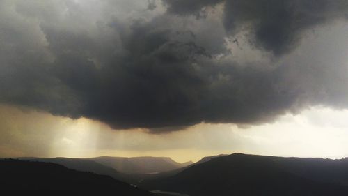 Scenic view of silhouette mountains against storm clouds