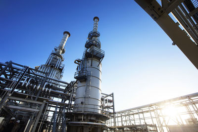 Low angle view of power station against sky on sunny day