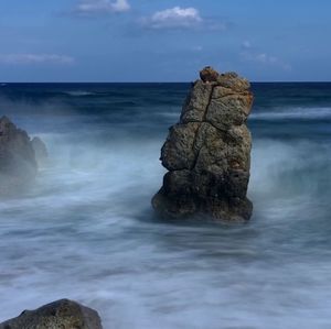 Rock formation on beach against sky