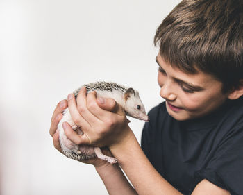 Close-up of boy carrying young hedgehog against white background