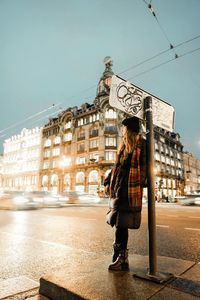 Woman standing on street against buildings in city