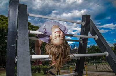 Portrait of girl playing on structure at park