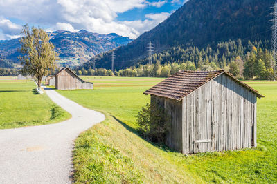 House on field by trees and houses against mountains