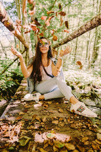 Full length of young woman with leaves on tree