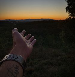 Midsection of person on field against sky during sunset