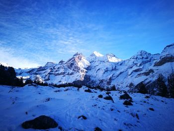 Scenic view of snow covered mountains against blue sky