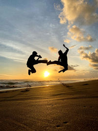 Silhouette men jumping against sky during sunset