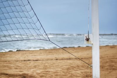Close-up of net on beach against sky