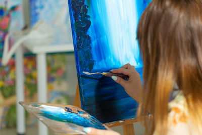 Midsection of woman standing against blue wall