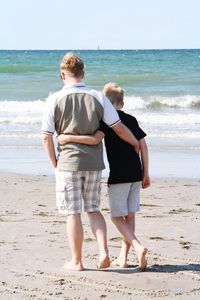 Rear view of father and son walking at beach