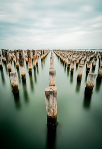 Panoramic view of wooden posts in sea against sky