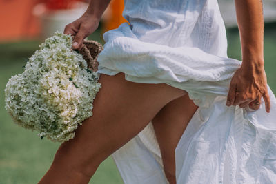 Low section of woman holding bouquet