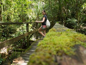 Woman standing on footbridge in forest