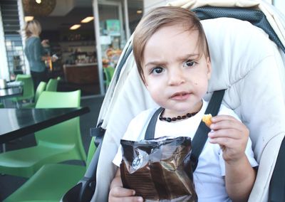 Little boy sitting in stroller eating potato chips