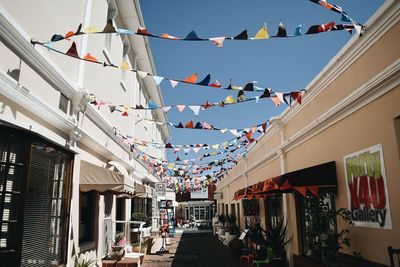 Low angle view of flags hanging amidst buildings in city