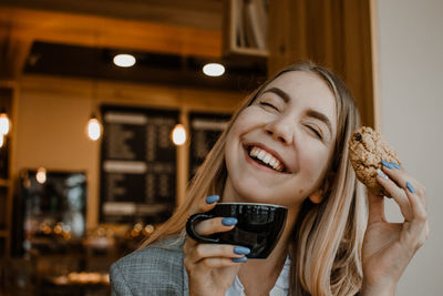 Smiling young woman holding biscuit