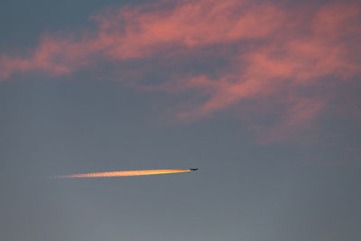 Low angle view of airplane flying against sky during sunset