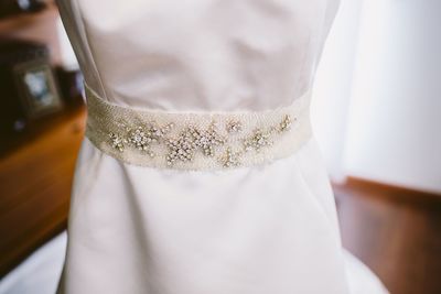 Midsection of bride wearing wedding dress at home