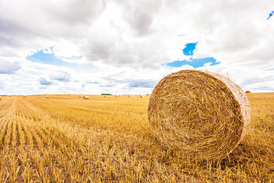 Hay bales on field against sky