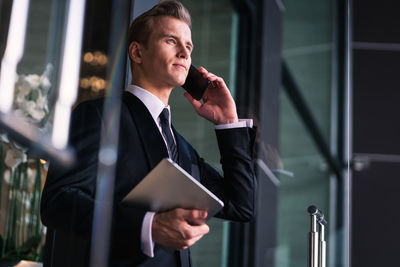 Handsome businessman listening over phone in office