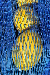 Close-up of buoy by in blue fishing net