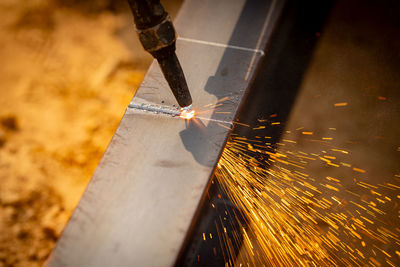 Skilled welder cuts metal with a gas torch in industrial workshop. sparks fly during precision