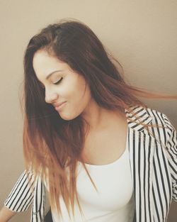 Young woman with dyed hair standing by wall