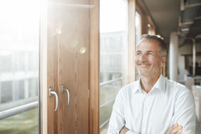 Portrait of smiling man standing against window