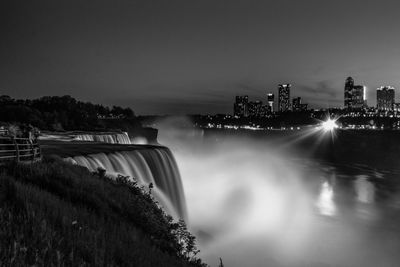 Long exposure of waterfall with city buildings seen in background