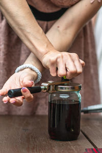 Midsection of woman opening bottle lid