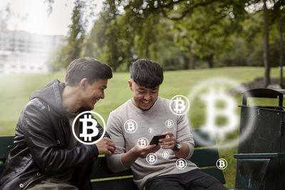 Male friends checking bitcoin crypto currency rates on phone