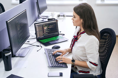 Side view of woman using laptop at office