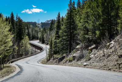 Road amidst trees and mountains against sky