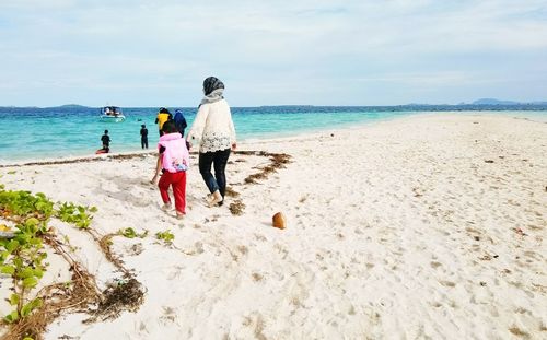 Rear view of women on beach against sky